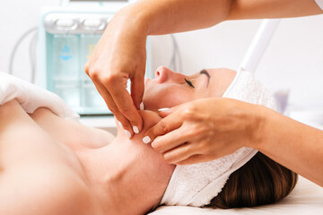 The cosmetologist gives a facial massage to the client. Side view and close up. Concept of cosmetology and treatment
