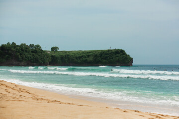 An ideal tropical sandy beach for surfing on the ocean. Beautiful clear turquoise water and waves.