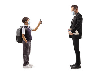 Schoolboy wearing a protective face mask and showing a mobile phone to a teacher
