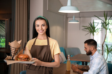 Young waitress with dish in restaurant
