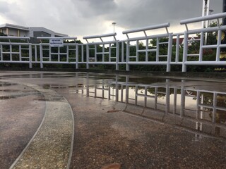 Obraz premium Puddle that reflects the picture of the white iron fence after the rain.