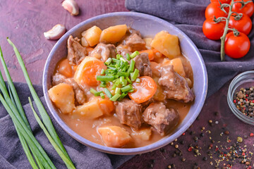 Bowl with tasty beef stew on color background
