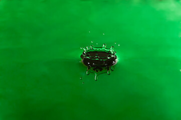 Drop green color falling and forming waves ripples