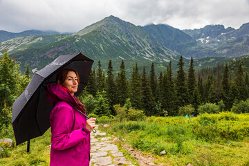 Beautiful mature woman with the umbrella in the mountain scenery