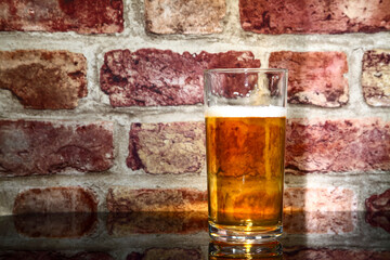 Glass of freshly poured lager on a glass table top