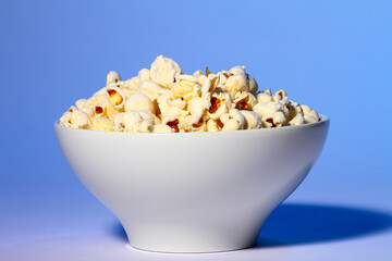 Bowl of fresh popcorn isolated on a blue background