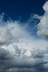 Beautiful blue sky background at daylight with white cumulus clouds. Vertical orientation