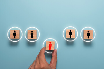 Hand holding and move red manager icon on wooden cube block between black subordinate employees....