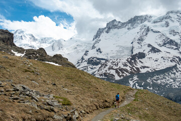 Fototapeta na wymiar Woman trail runner in alpine mountains with snow and glacier in the background