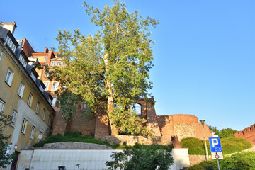The historic defensive walls of the Warsaw Barbican and burgher houses in the Old Town in the light...