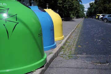 Fototapeta na wymiar Three colored bins for sorting waste located in the city on the street.Trash Containers for Garbage Separation -- three colors for plastic, metal and burnables.
