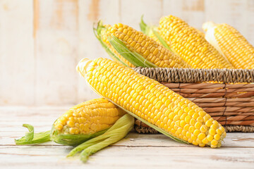 Basket with fresh corn cobs on table