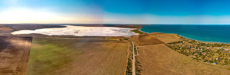 white-blue salty lake Tobechikskoe surrounded by hilly terrain with rare desert vegetation in the south of the Kerch Peninsula - aerial drone view view on a sunny summer day