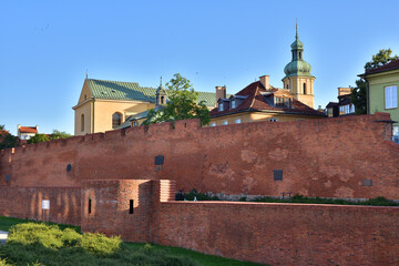The historic defensive walls of the Warsaw Barbican and burgher houses in the Old Town in the light...