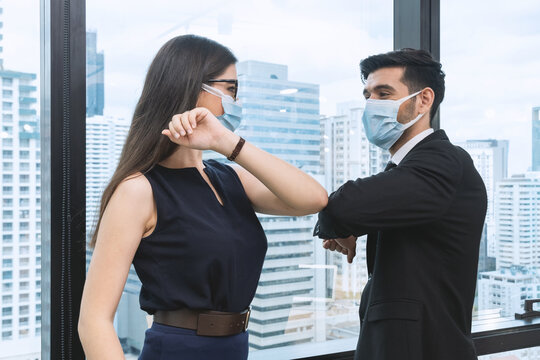 Office Man And Woman Wearing Face Mask Greeting By Elbow Bump.