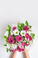 Hands holding beautiful flowers bouquet: roses, chrysanthemum on light background. Flat lay,copy space