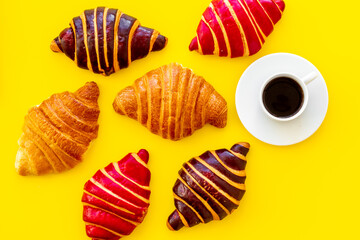Set of coffee with croissants - chocolate, berry, classic - on yellow table