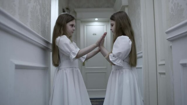 Zombie twin sisters playing clap game in empty hallway, creepy horror atmosphere