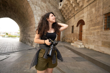 Fototapeta na wymiar Female tourist is visiting historical places with camera. Photographer who visits historical places. The blogger who is happy to see new places. A woman going on a trip with a backpack and a camera. 