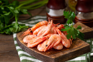 Shrimp on a wooden Board on a brown wooden table. Lots of prawns on the serving Board. Prawns close up