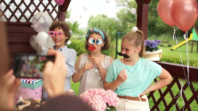 Woman takes a photo by smartphone of her daughter's birthday. Birthday party, photo booth, photo props, candy bar, catering concept