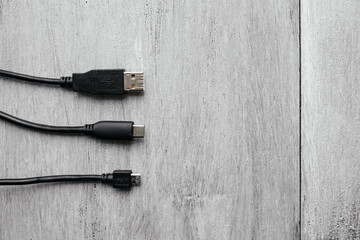 Different USB cables with different connectors on a white wooden background. Different ports of one interface. USB type C, type A and micro usb.