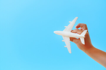 A white toy plane in a child's hand against a blue sky.