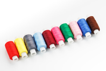 Sewing threads of different colors on reels on a white background. Free space, close-up. Isolate