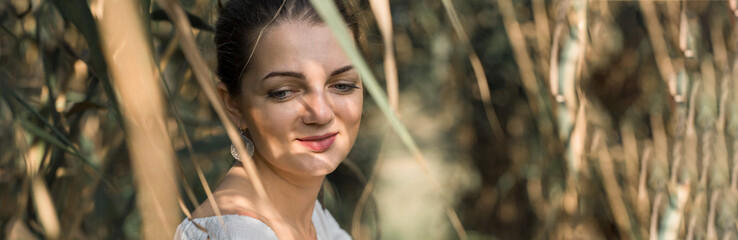 Portrait of a young beautiful girl in reeds in retro style in a light dress.
