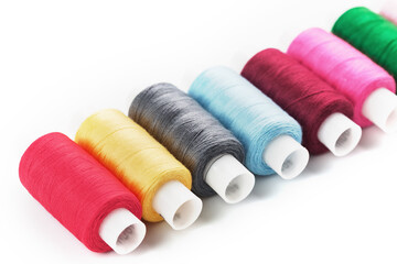 Sewing threads of different colors on reels on a white background. Free space, close-up. Isolate