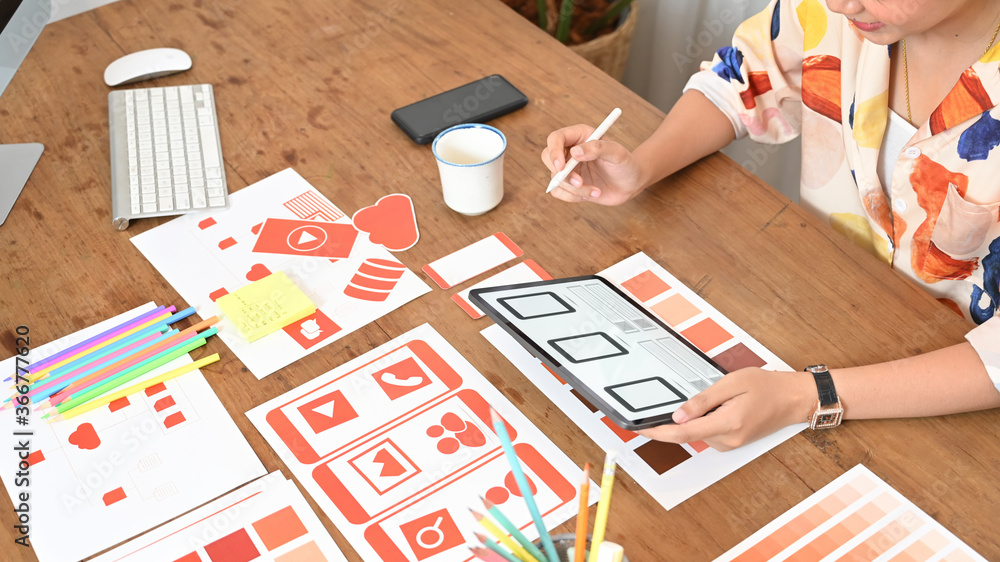 Poster cropped image of a woman is using a computer tablet with an interface icon on the screen at the wood