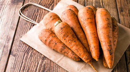 Fresh dirty carrots on wooden background