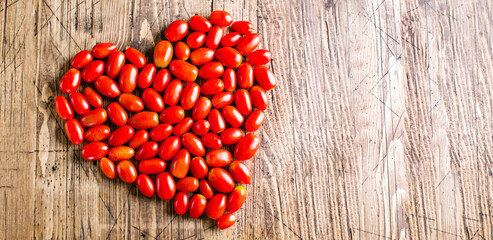 Heart shaped cherry tomatoes on wooden background, long banner, copy space