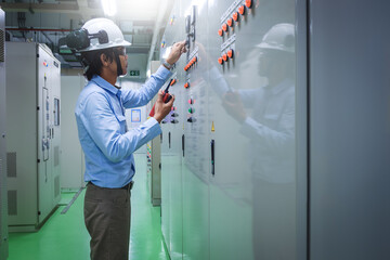 Asia technician monitoring industrial plant in electrical substation room with control panel,...