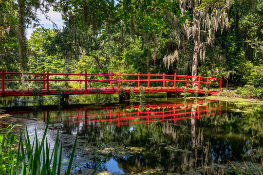 A Beautiful Red Foot Bridge With Reflection Crosses A Pond On A Plantation Near Charleston, South Carolina.