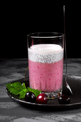 Pudding with chia seeds and mashed cherry on the grey table. Layered dessert