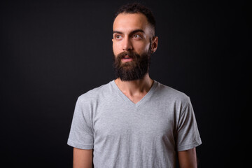 Young handsome Persian man with dreadlocks against black background