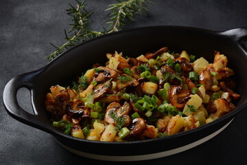 Fried potatoes with mushrooms in a plate/and frying bowl with herbs.