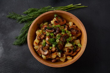 Fried potatoes with mushrooms in a wooden bowl. Rustic style.
