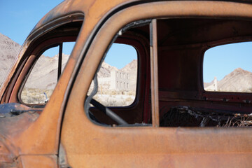 Fototapeta na wymiar View through antique rusty truck of ruins of ghost town in Rhyolite Nevada