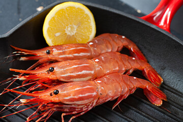 Spot prawns in sharp colour on black coloured cast iron pan, creating a strong contrast in colour.