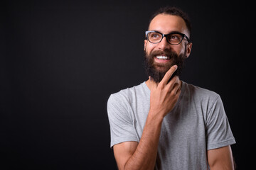 Young handsome Persian man with dreadlocks against black background