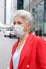 elegant middle-aged woman on the street in a medical mask