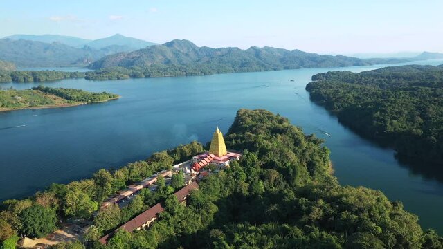 Aerial View drone point of interst shot of golden pagoda on island surrounding with lake and mountain at Sangkhaburi, Kanchanaburi, Thailand
