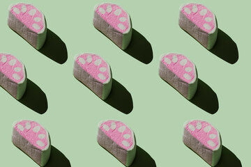 Pattern of tasty marshmallows with hard shadows on a pastel green background.