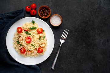 
pasta with salmon and tomatoes on a stone background with copy space for your text