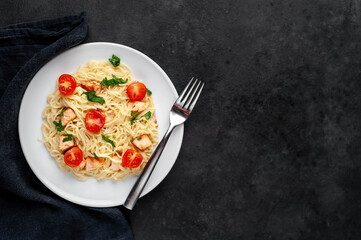 
pasta with salmon and tomatoes on a stone background with copy space for your text