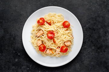 pasta with salmon and tomatoes on a stone background