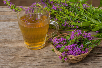Fireweed is a healthy herbal tea. Mug of traditional russian drink ivan tea on a wooden background with fireweed flowers