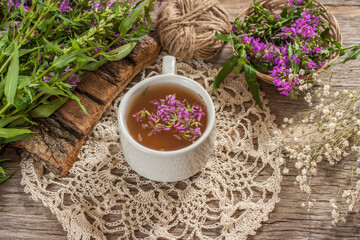 Fireweed is a healthy herbal tea. Mug of traditional russian drink ivan tea on a wooden background with fireweed flowers